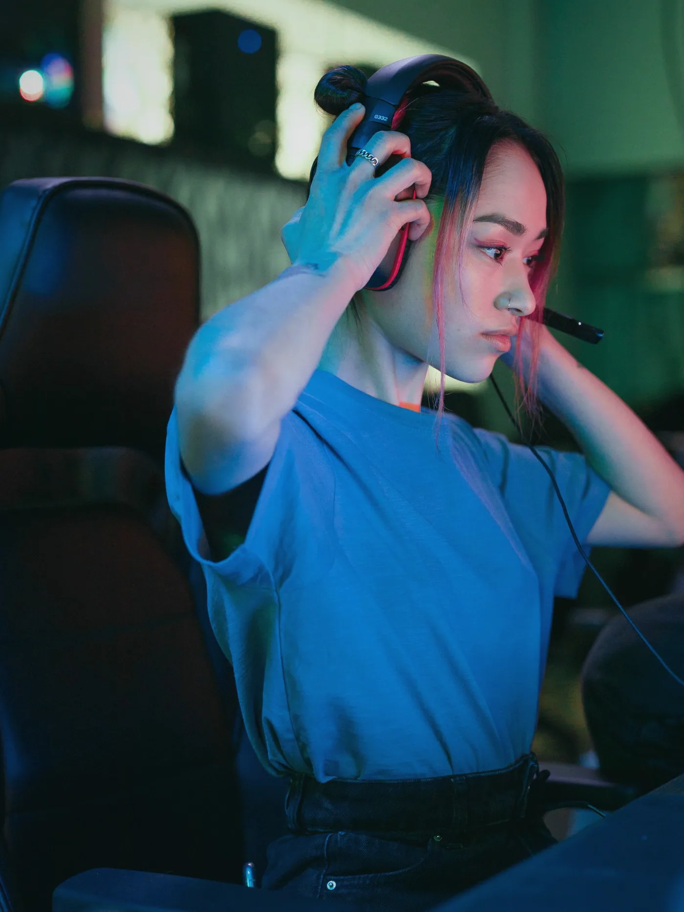A player in a headset at a gaming PC, lit by the screen in a dim room